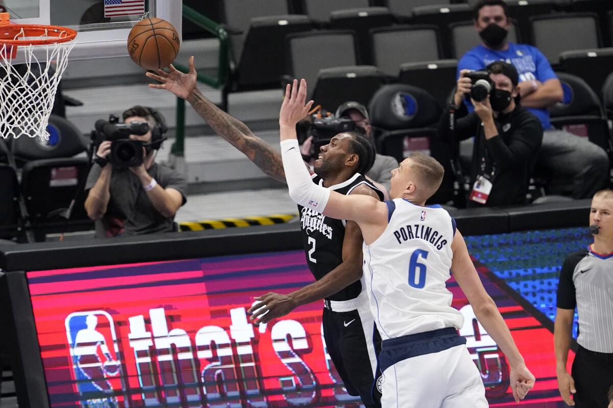 Clippers forward Kawhi Leonard takes a shot as Dallas Mavericks center Kristaps Porzingis defends.