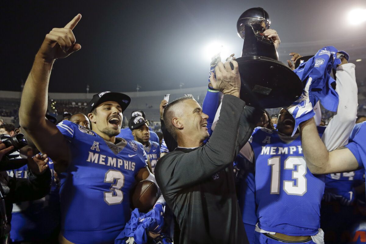 Memphis quarterback Brady White (3) celebrates as coach Mike Norvell lifts the trophy after the Tigers beat Cincinnati on Saturday.