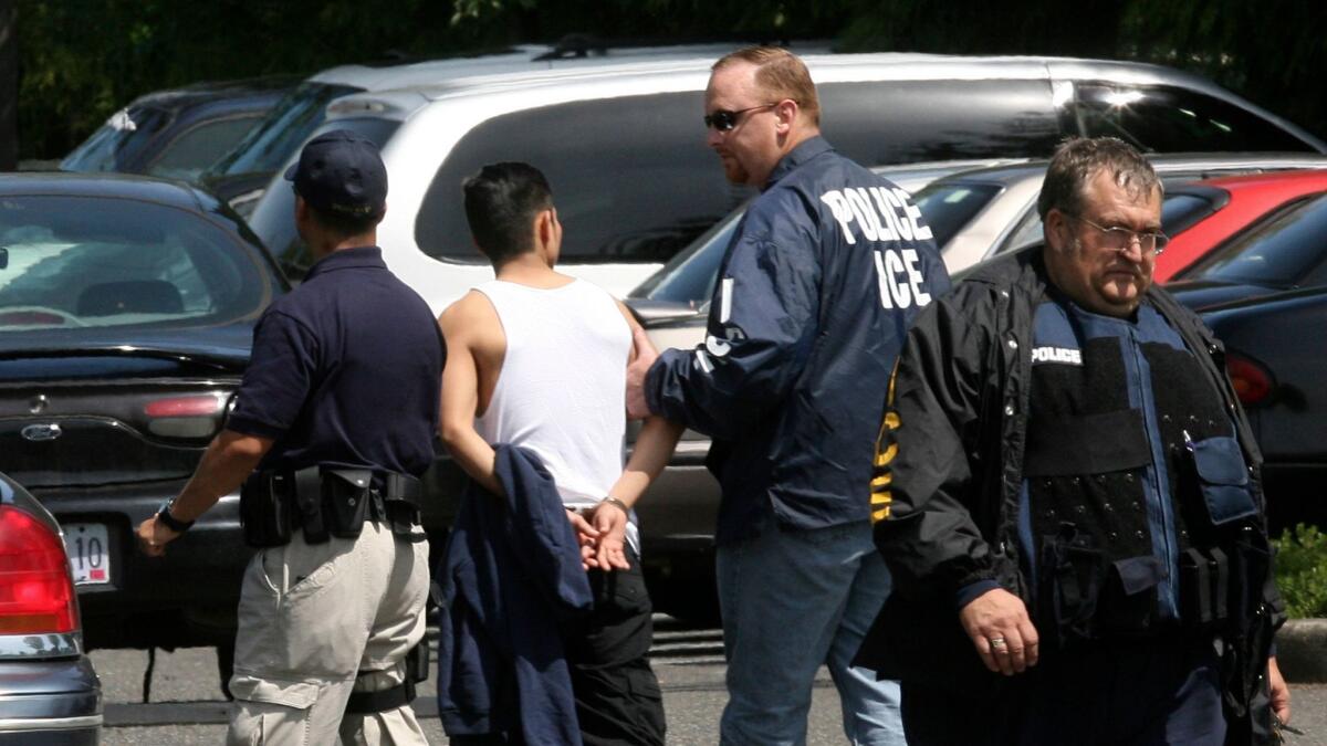Federal immigration agents walk a man in handcuffs on June 12, 2007, in Portland, Ore.