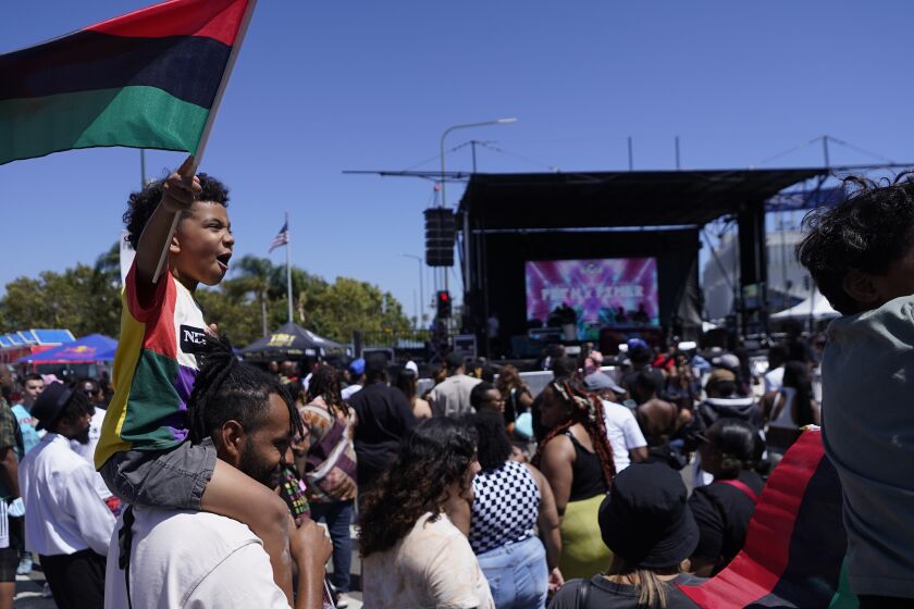 Archivo - Julien James carga a su hijo, Maison, de 4 años, quien sostiene una bandera panafricana, durante una conmemoración del Juneteenth el 18 de junio de 2022 en Leimert Park en Los Ángeles. (AP Foto/Damian Dovarganes, Archivo)