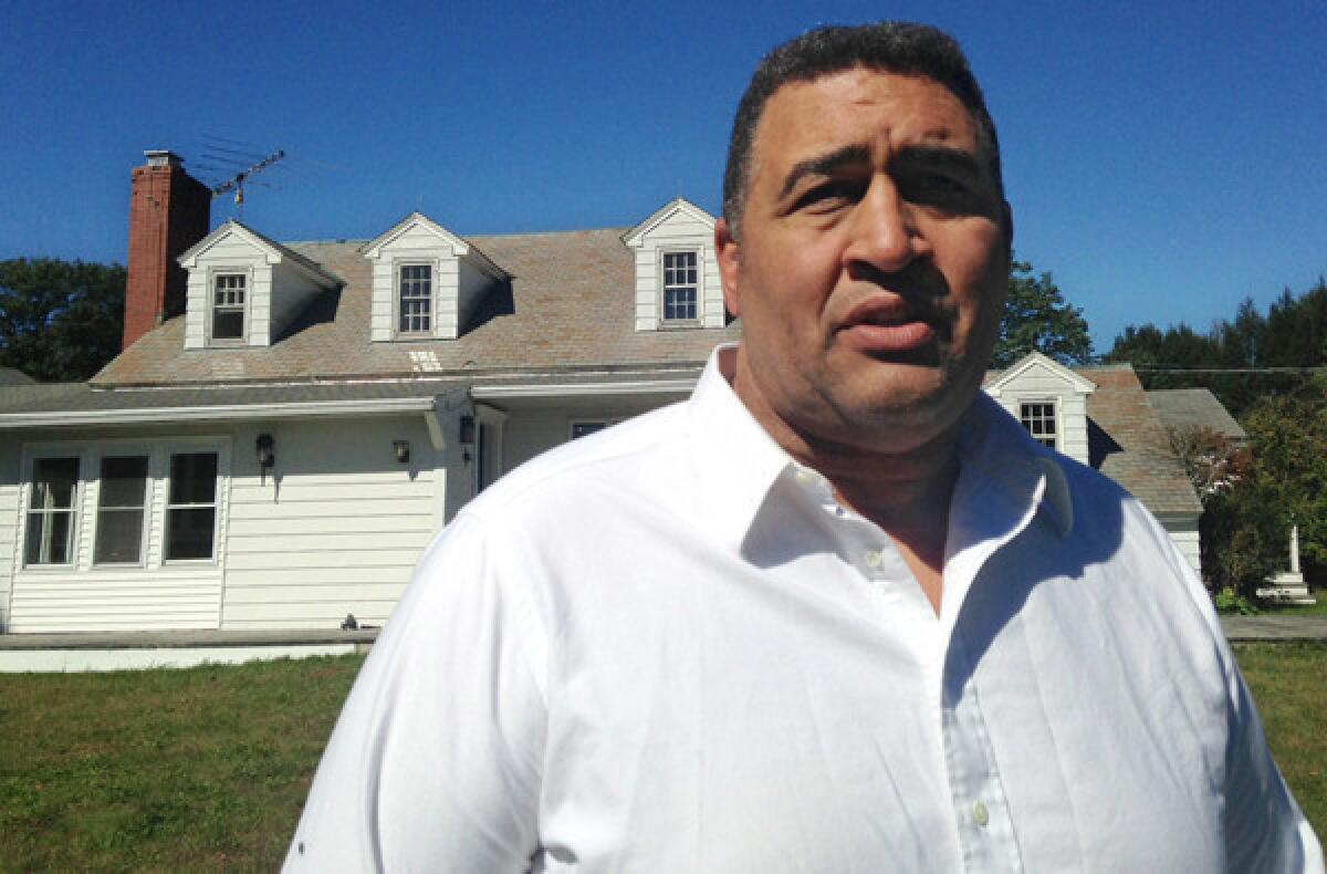 Former NFL offensive lineman Brian Holloway stands in front of his vacation home in Stephentown, N.Y.
