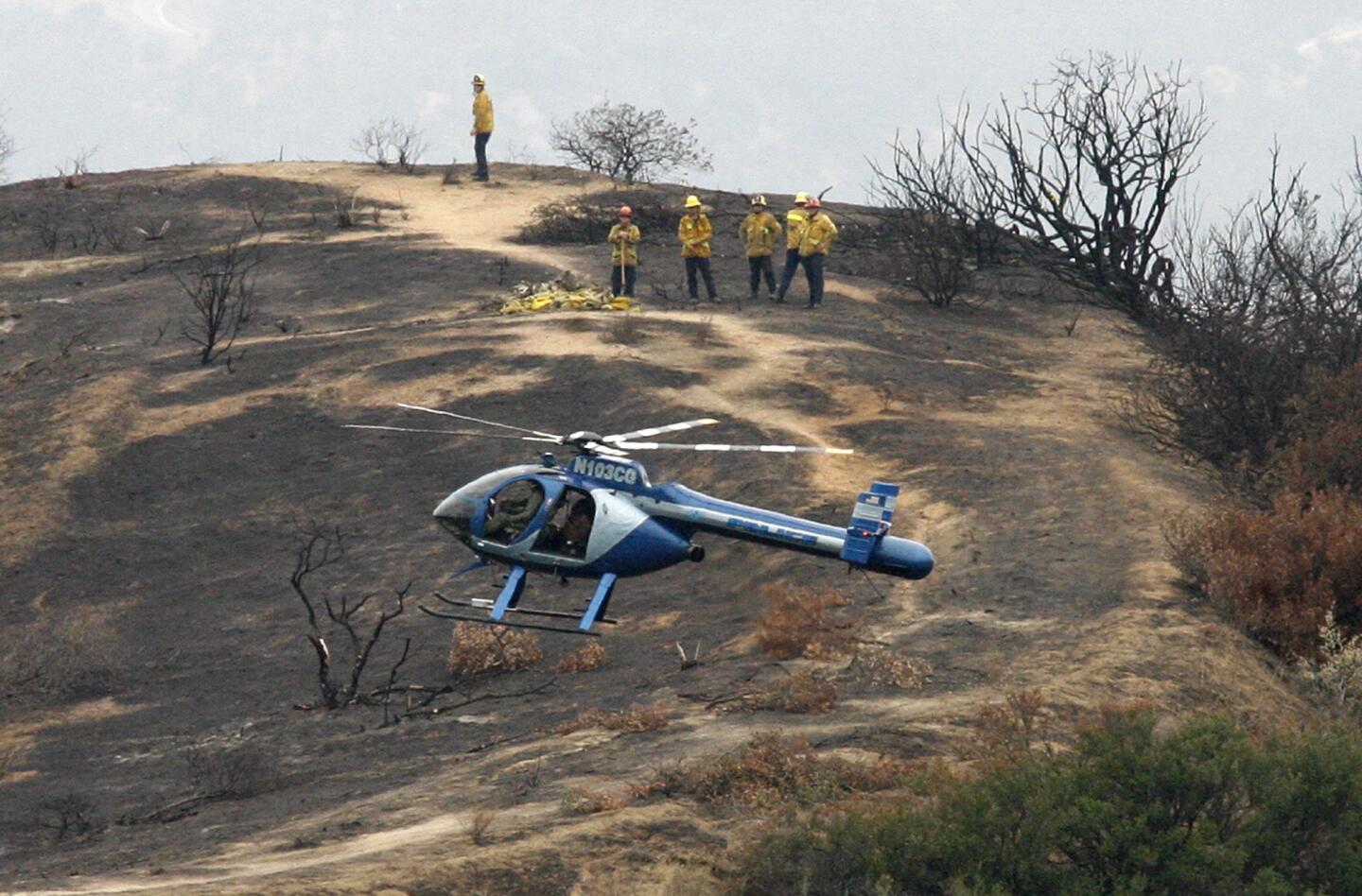 A Glendale police helicopter gets into position to assist Glendale fire fighters fly a net filled with fire hose left by firefighters last week after the brush fire in the hills back to the helipad at by the water tank at Scholl Canyon in Glendale on Thursday, May 9, 2013. The Glendale Police Department used their helicopter to assist the Glendale Fire Department retrieve nearly 5,000 feet of hose used to fight the brush fires in Glenoaks Canyon last week.