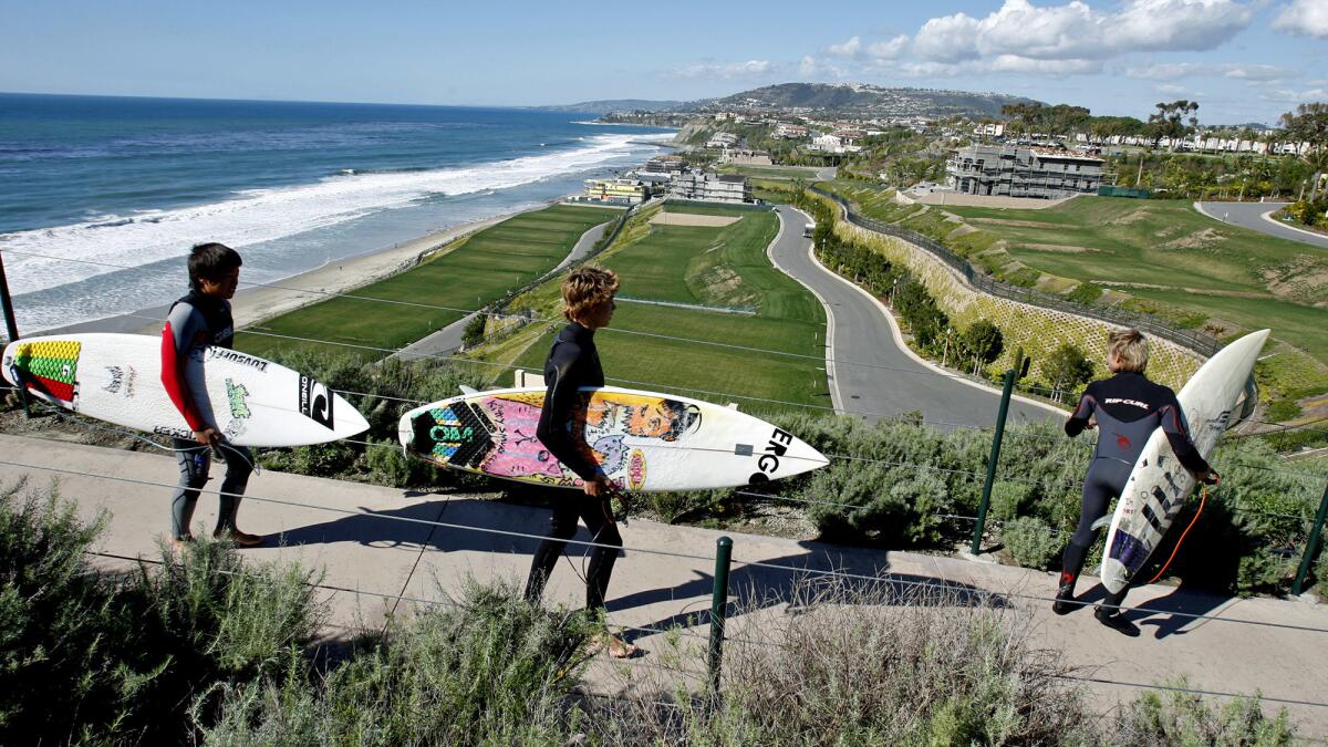 Surfers walk down a path at a Dana Point development in 2010. Developers were required to provide public access to the beach.