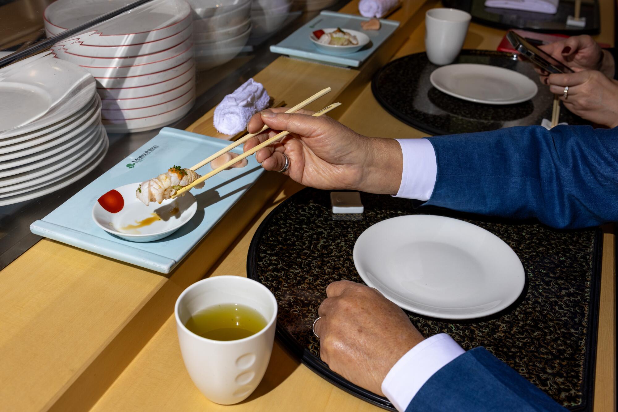 Mr. Chow picks up a piece of nigiri sushi at Matsuhisa in Beverly Hills. 