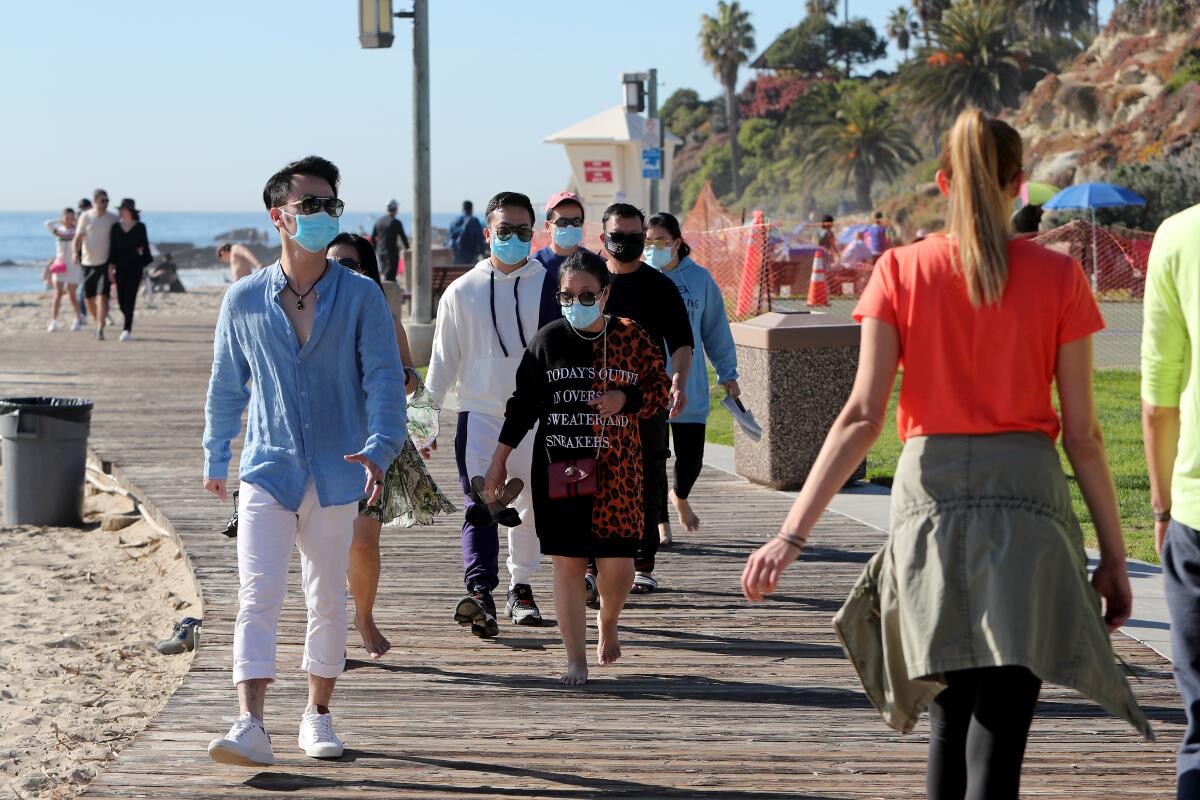 Visitors stroll at Laguna Main Beach in Laguna Beach on Saturday.