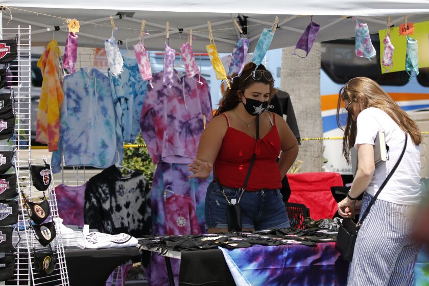 Taylor Medina of Chino Hills sells masks and other items of clothing at her stand Tayy Medd Shop, at the Pier Plaza in Huntington Beach on Friday, June 26, 2020.