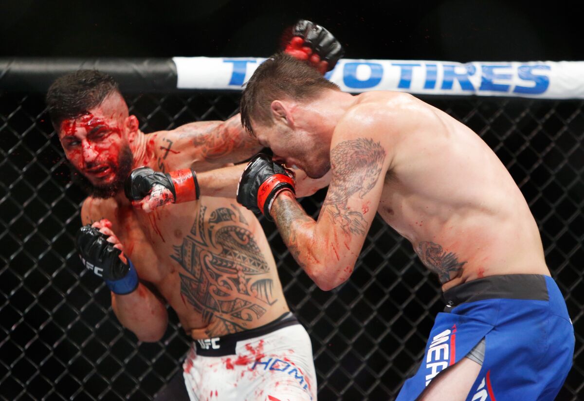 Tim Means trades punches with a bloody Sabah Homasi during their welterweight bout at the UFC 202.