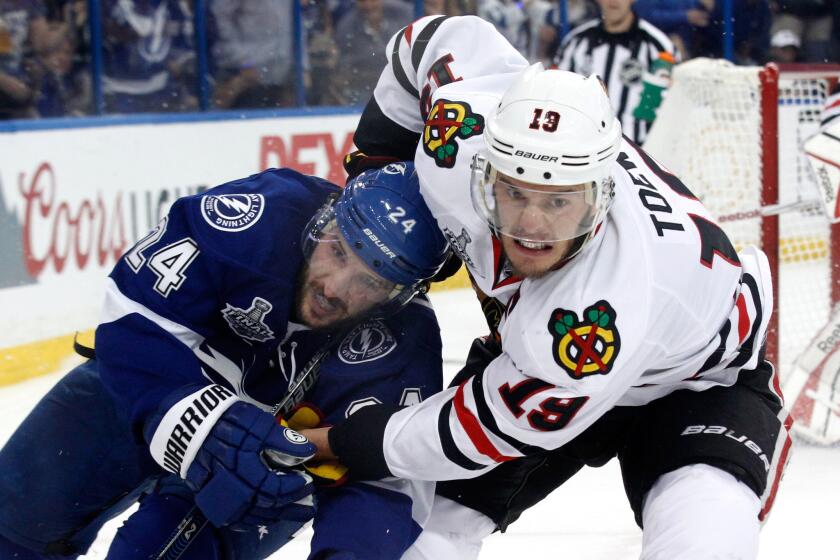 Lightning right wing Ryan Callahan (24) and Blackhawks center Jonathan Toews (19) tangle as they chase after the puck in Game 1.