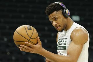 Milwaukee Bucks forward Giannis Antetokounmpo wears headphones and dribbles a basketball.