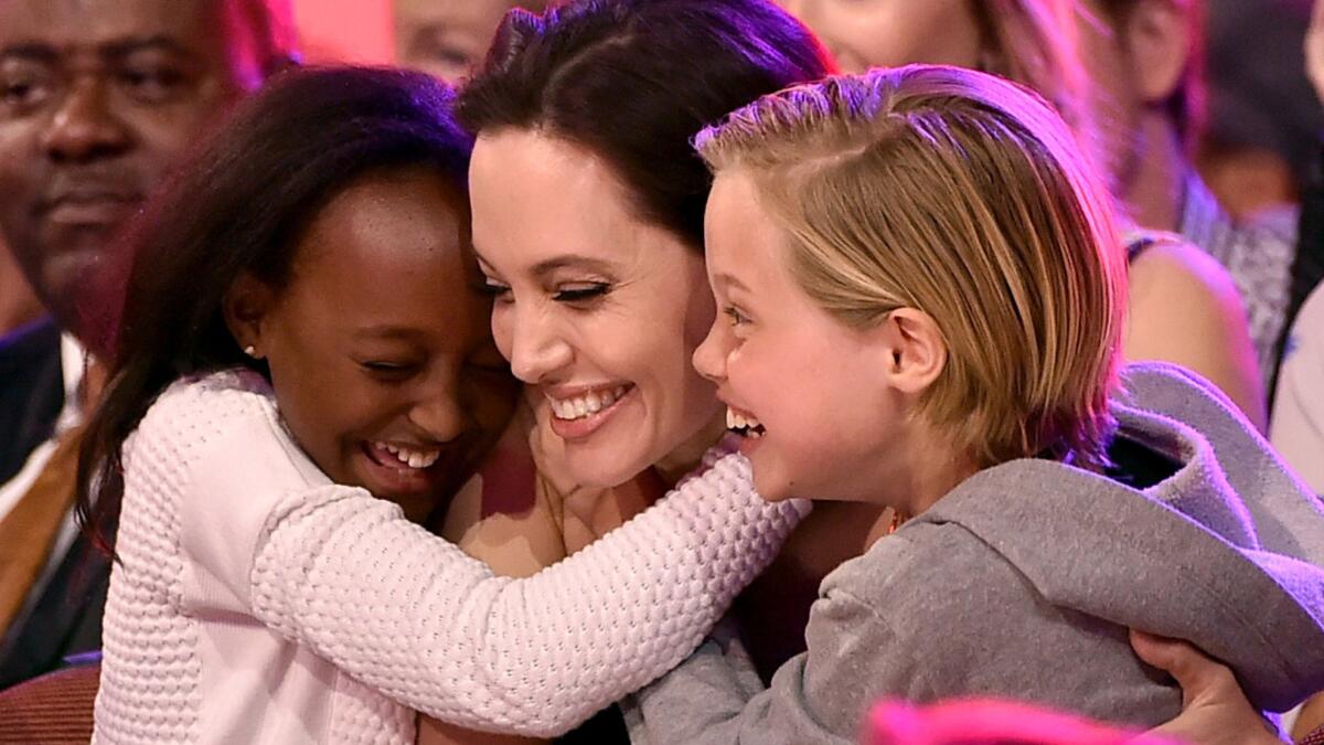 Zahara Jolie-Pitt, left, and sister Shiloh Jolie-Pitt hug their mother, Angelina Jolie, as she's announced as the year's favorite villain at the 28th Annual Kids' Choice Awards on Saturday in Inglewood.
