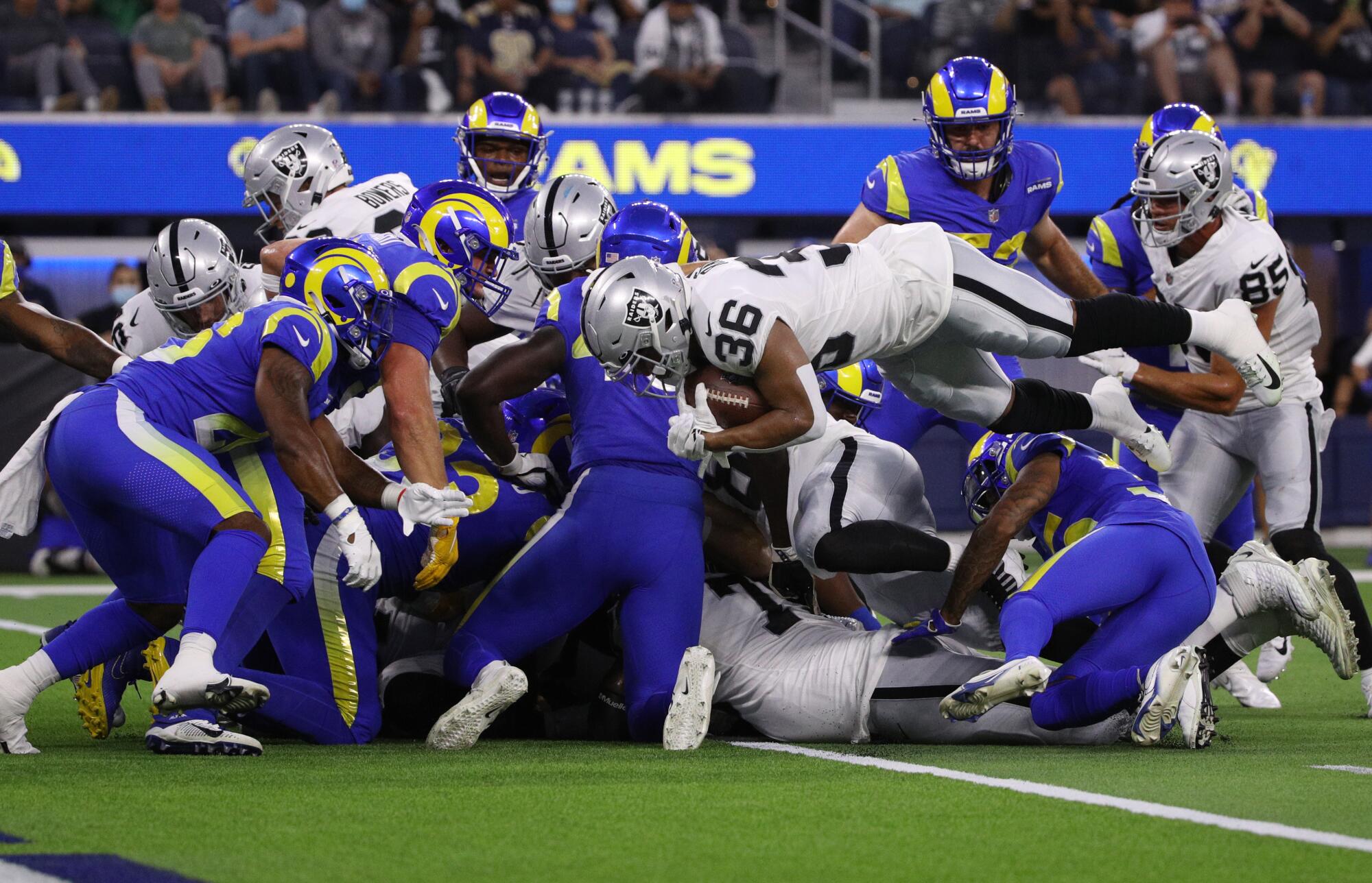 Raiders running back Trey Ragas leaps into the end zone to score against the Rams defense on fourth down.
