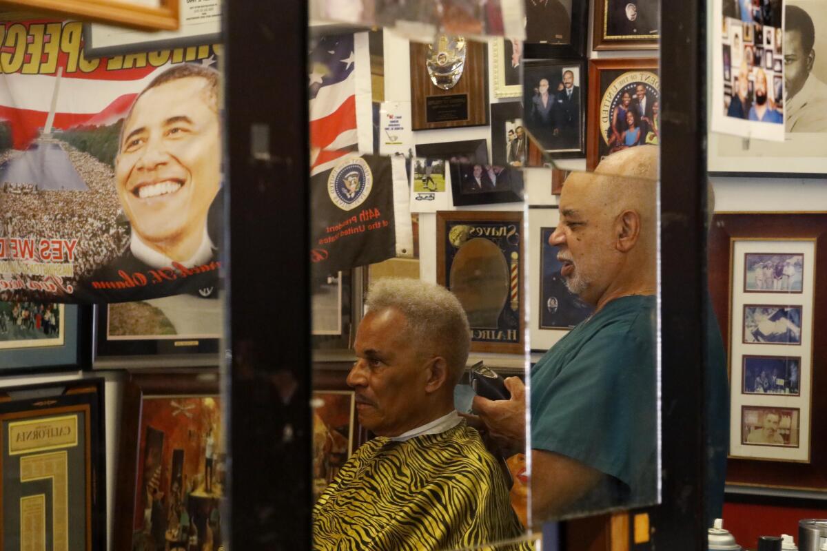 Lawrence Tolliver gives a haircut at his South L.A. barbershop