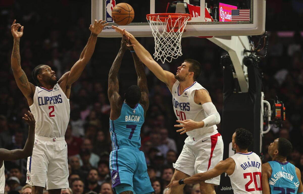 Clippers Kawhi Leonard and Ivica Zubac go for the block on Charlotte guard Dwayne Bacon.