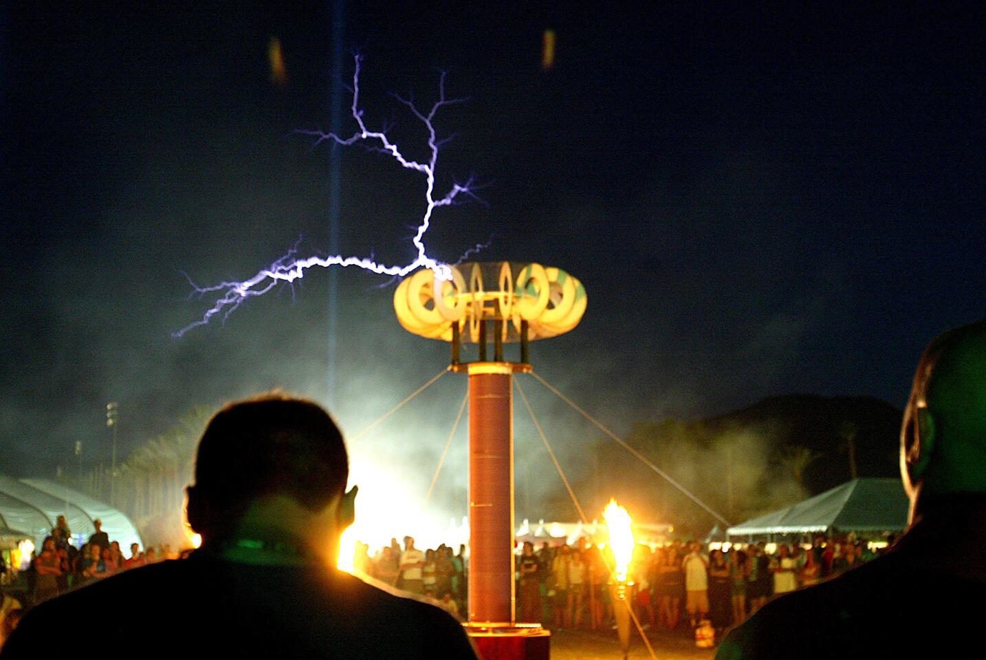 Flashes of lightning generated by artist Syd Klina hover above the crowd after the sun sets at the Coachella Music and Arts Festival in Indio, Sunday, May 2, 2004.