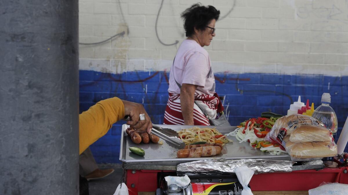 A food vendor prepares hot dogs on a sidewalk in Los Angeles. The Huntington Beach City Council on Tuesday created a temporary permit process to allow sidewalk vendors to sell food and other goods, with strict restrictions.