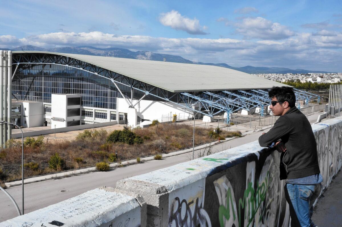 An Afghan refugee looks over the Galatsi Olympic Hall, one of three 2004 Athens Summer Games sites serving as way stations for some of the hundreds of thousands headed toward Germany and Sweden.