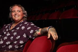 A smiling Asher Phoenix sits in an empty Colony Theatre in Burbank.