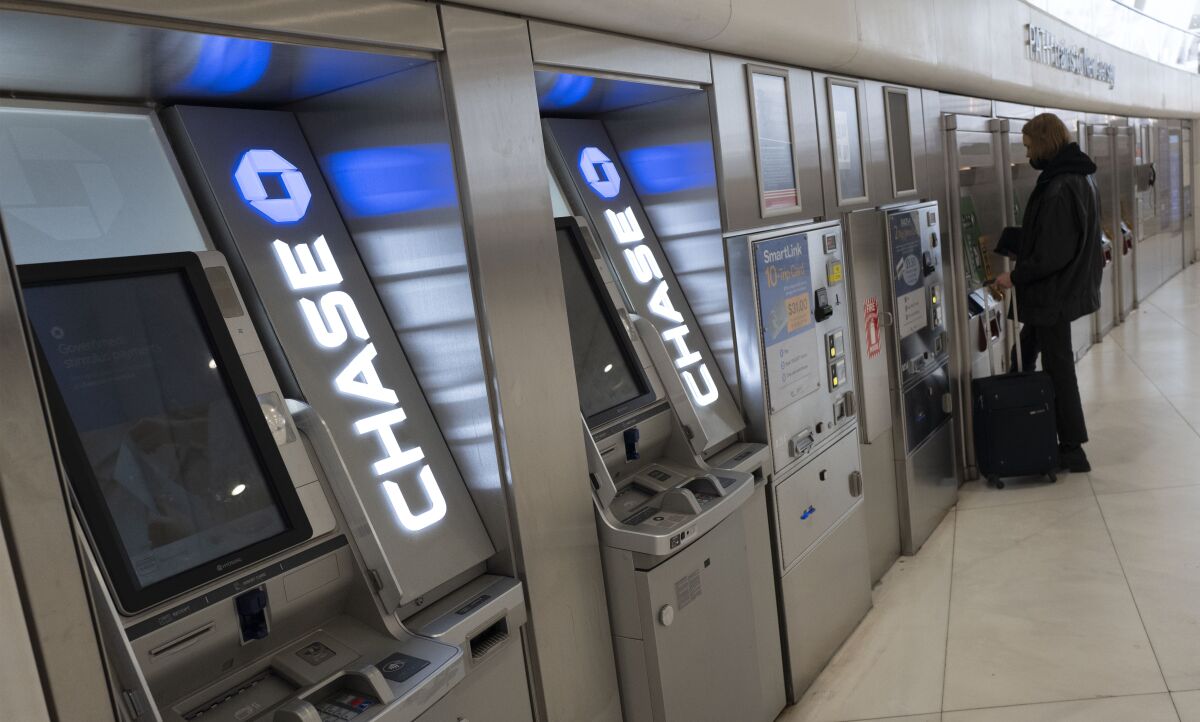 Chase Bank ATMs are shown, Thursday, March 25, 2021, in New York. JPMorgan Chase said, Wednesday, April 13, 2022, its first quarter profits dropped by 42% from last year, partly because the bank had to write down nearly $1.5 billion in assets due to higher inflation and the Russian-Ukrainian War. The nation’s largest bank by assets said it earned a profit of $8.3 billion, or $2.63 per share, down from a profit of $14.3 billion, or $4.50 a share, in the same period a year earlier.(AP Photo/Mark Lennihan)