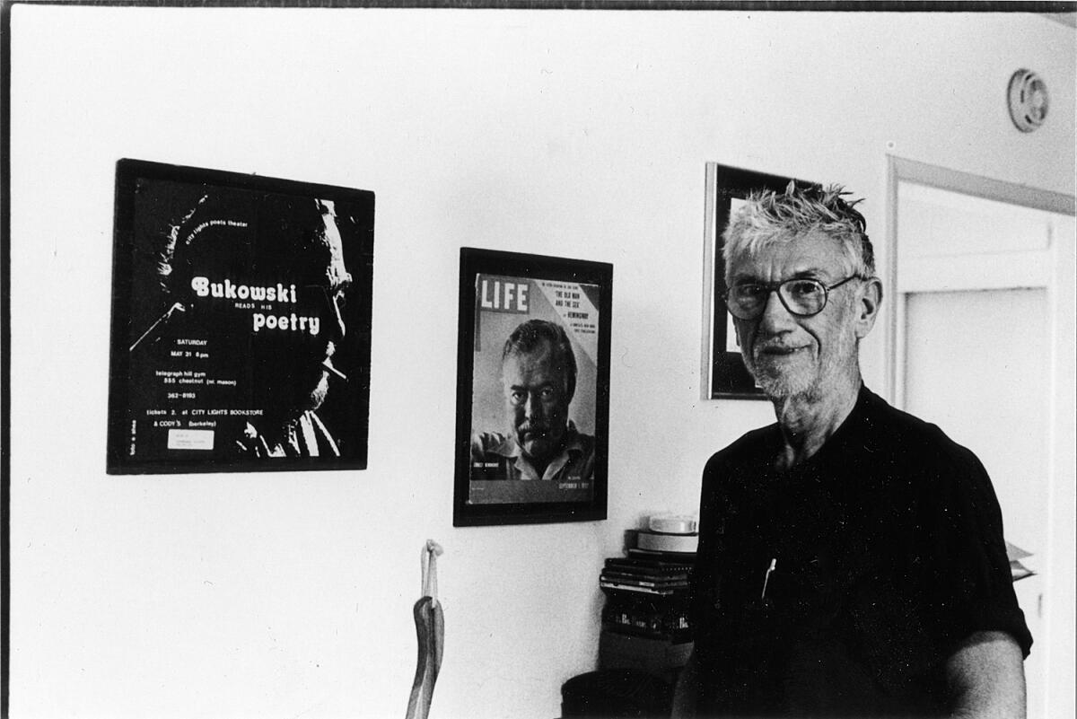 Gerald Locklin with portraits of Charles Bukowski, left, and Ernest Hemingway.