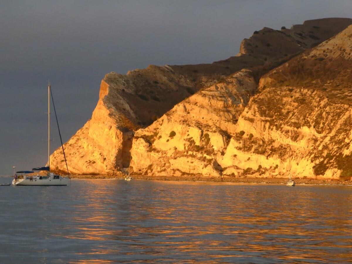 A large sandstone cliff on the water at sunrise 