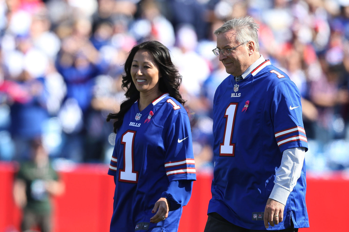 Bill owners Kim and Terry Pegula walk on the field before a game.