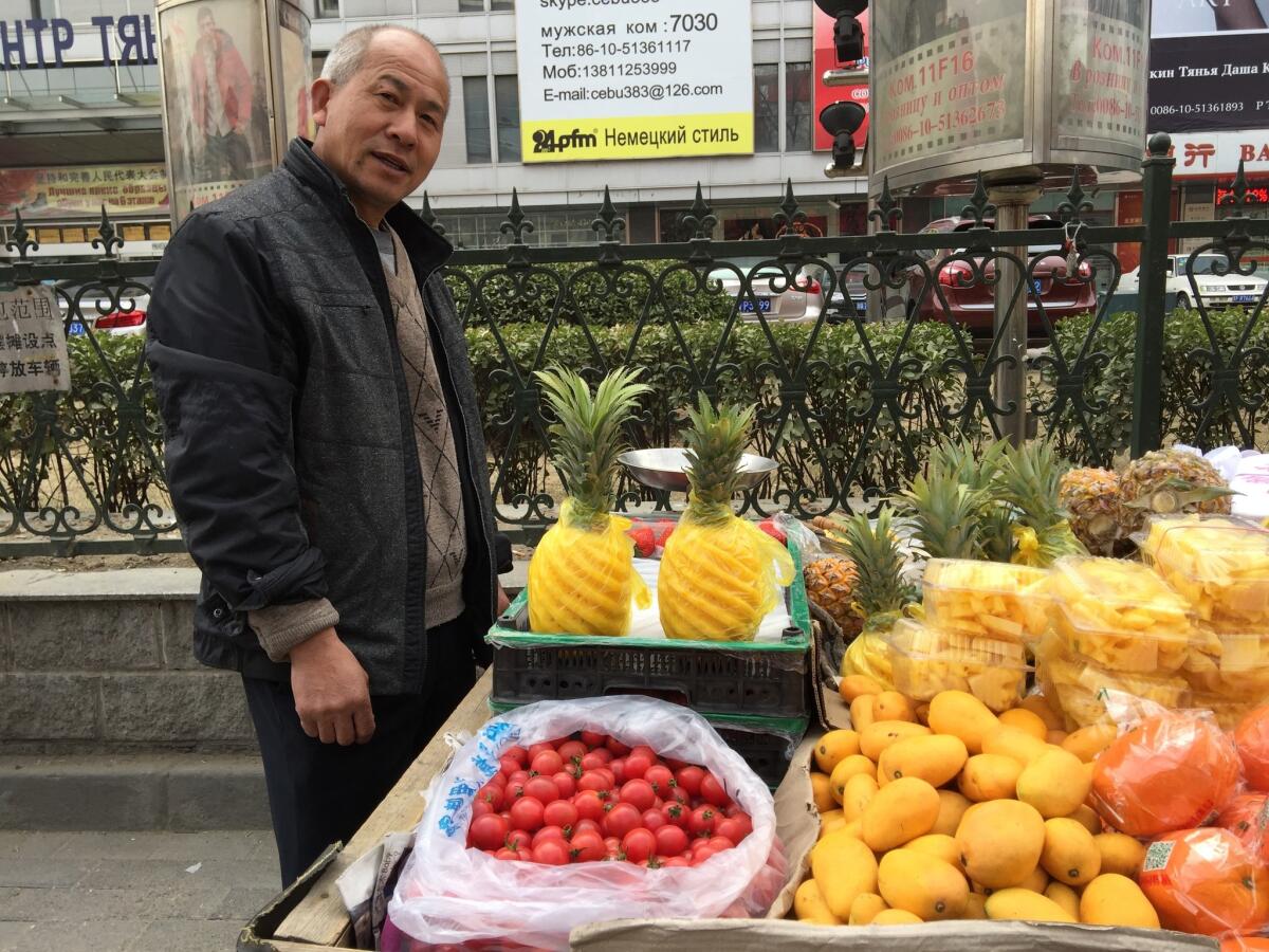 A man sells pineapples, mangoes and other fruit in Beijing.