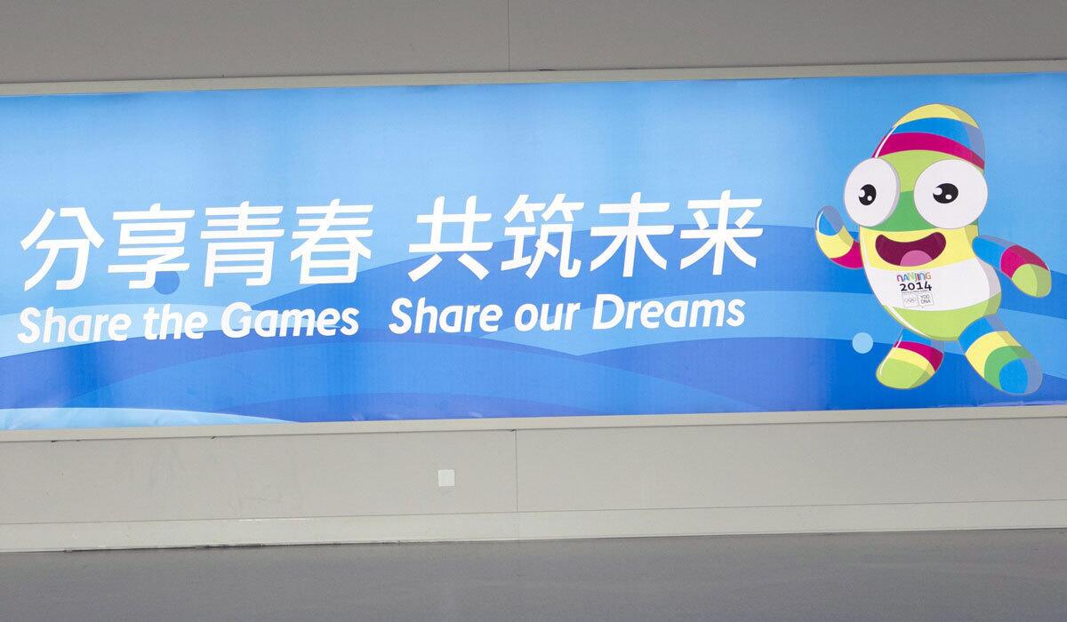 A sign for the 2014 Youth Olympic Games featuring official mascot Nanjing Lele at the airport in Nanjing, China.