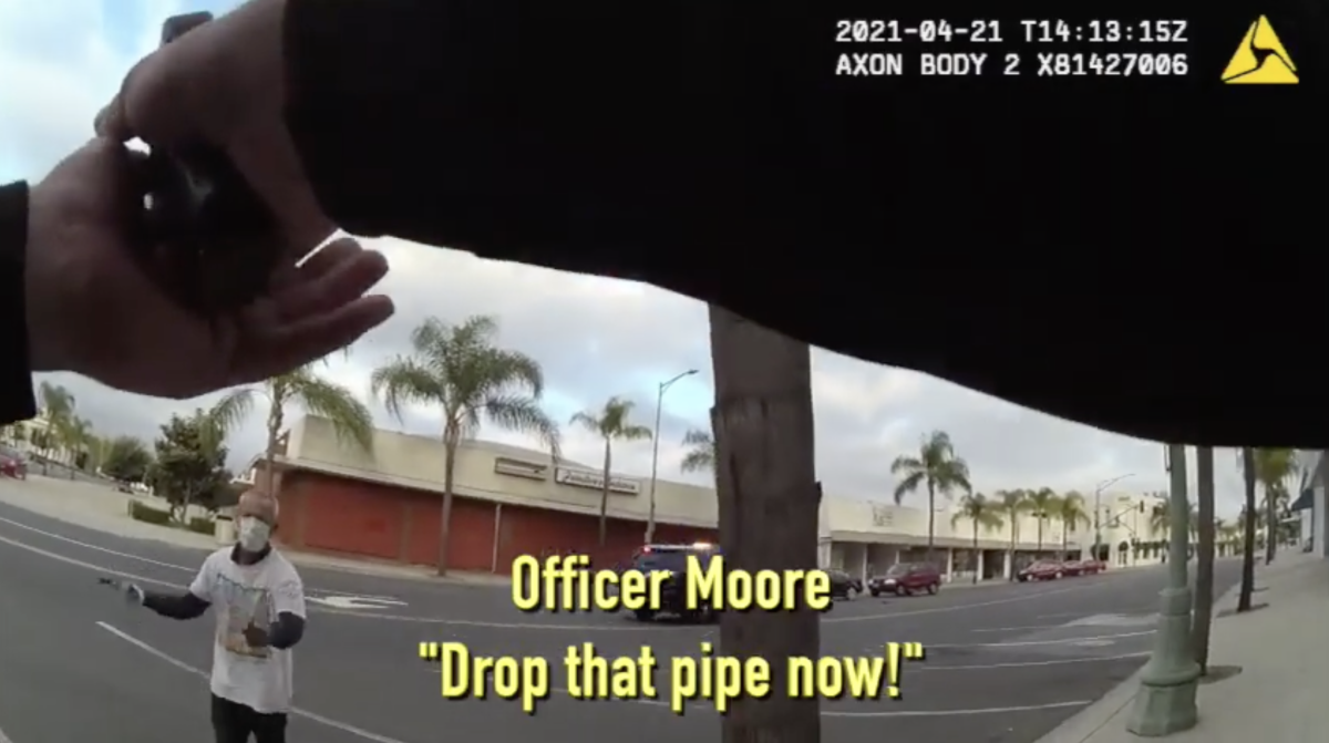 Image from body police cam video of officer pointing his gun at a man in the street