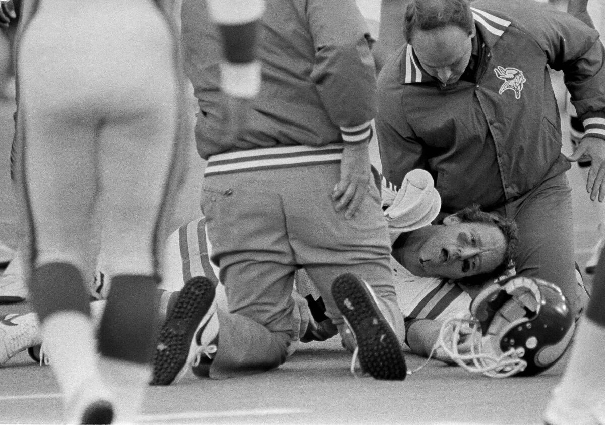 A team trainer attends to Archie Manning after the Vikings quarterback was sacked during a game against the Bears in 1984.