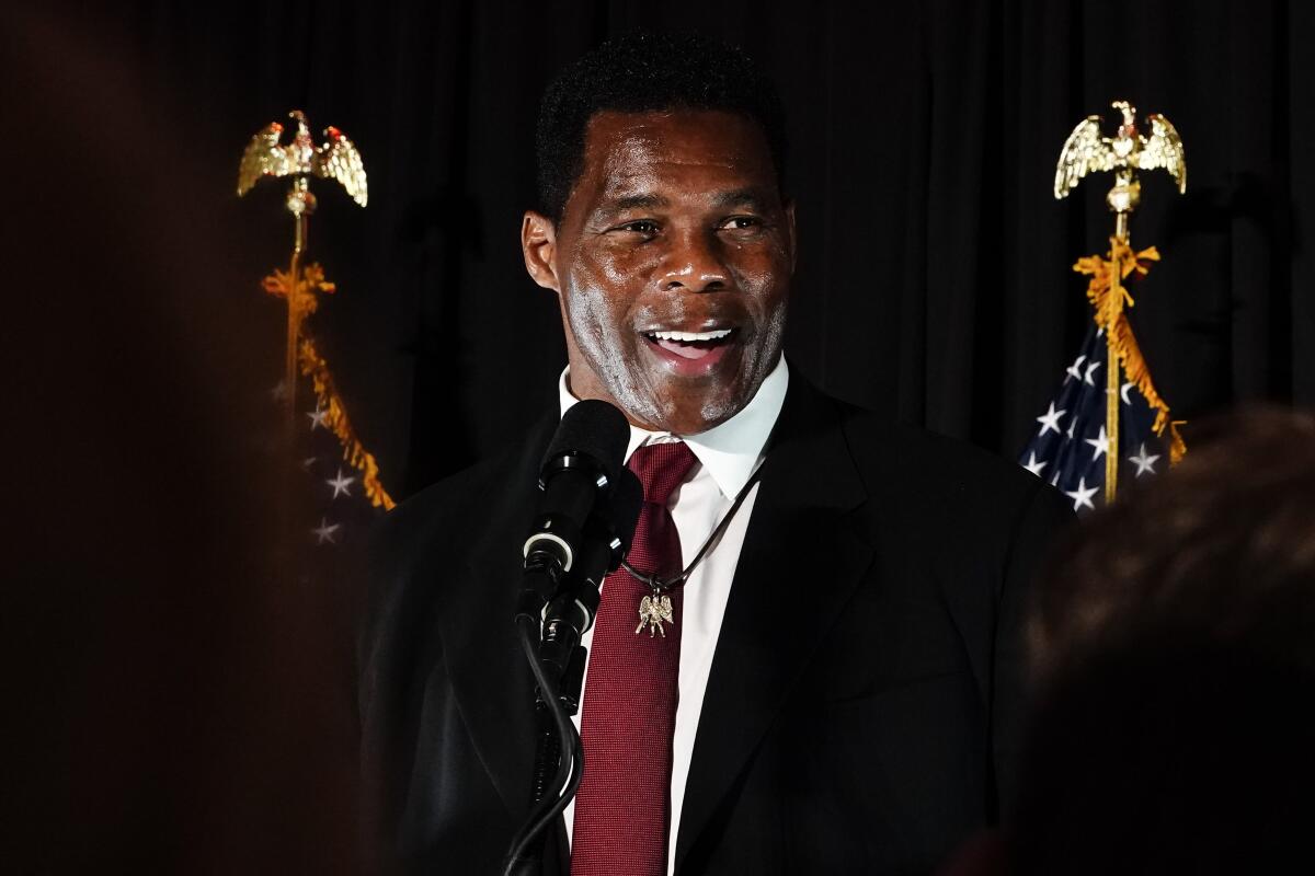 Herschel Walker in a suit, flanked by U.S. flags