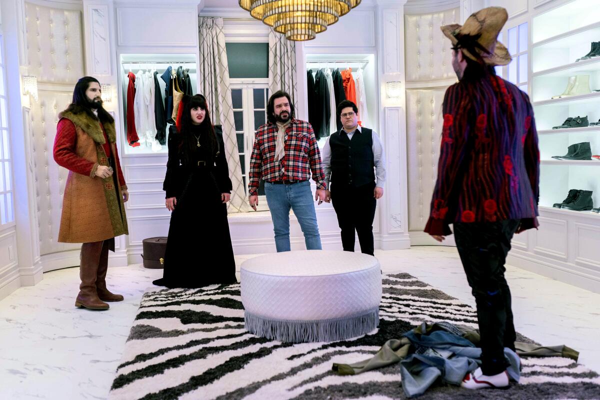 The three vampires and Guillermo the familiar stand in a luxe, all-white room talking to a home renovation expert.