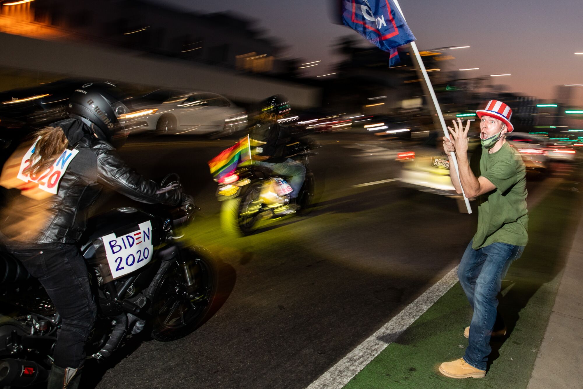 A supporter of President Trump waves a flag as Joe Biden supporters ride by on motorcycles in Beverly Hills