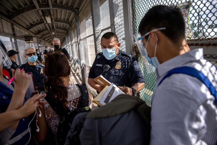 MATAMOROS, MEXICO - FEBRUARY 25: A U.S. Customs and Border Protection officer speaks with immigrants at the U.S.-Mexico border as a group of at least 25 asylum seekers were allowed to travel from a migrant camp in Mexico into the United States on February 25, 2021 in Matamoros, Mexico. The group was the first allowed to cross into south Texas as part of the unwinding of the Trump administration's Migrant Protection Protocols, (MPP), also known as the 'Remain in Mexico' immigration policy. Many of the asylum seekers had been waiting in the squalid camp alongside the Rio Grande for more than a year. Last week the first group of 25 MPP immigrants entered from Tijuana into San Ysidro, California. (Photo by John Moore/Getty Images)