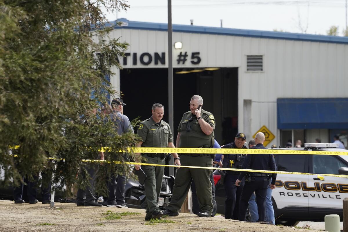 Authorities from various agencies gather at the command post next to a local fitness center in Roseville, Calif.