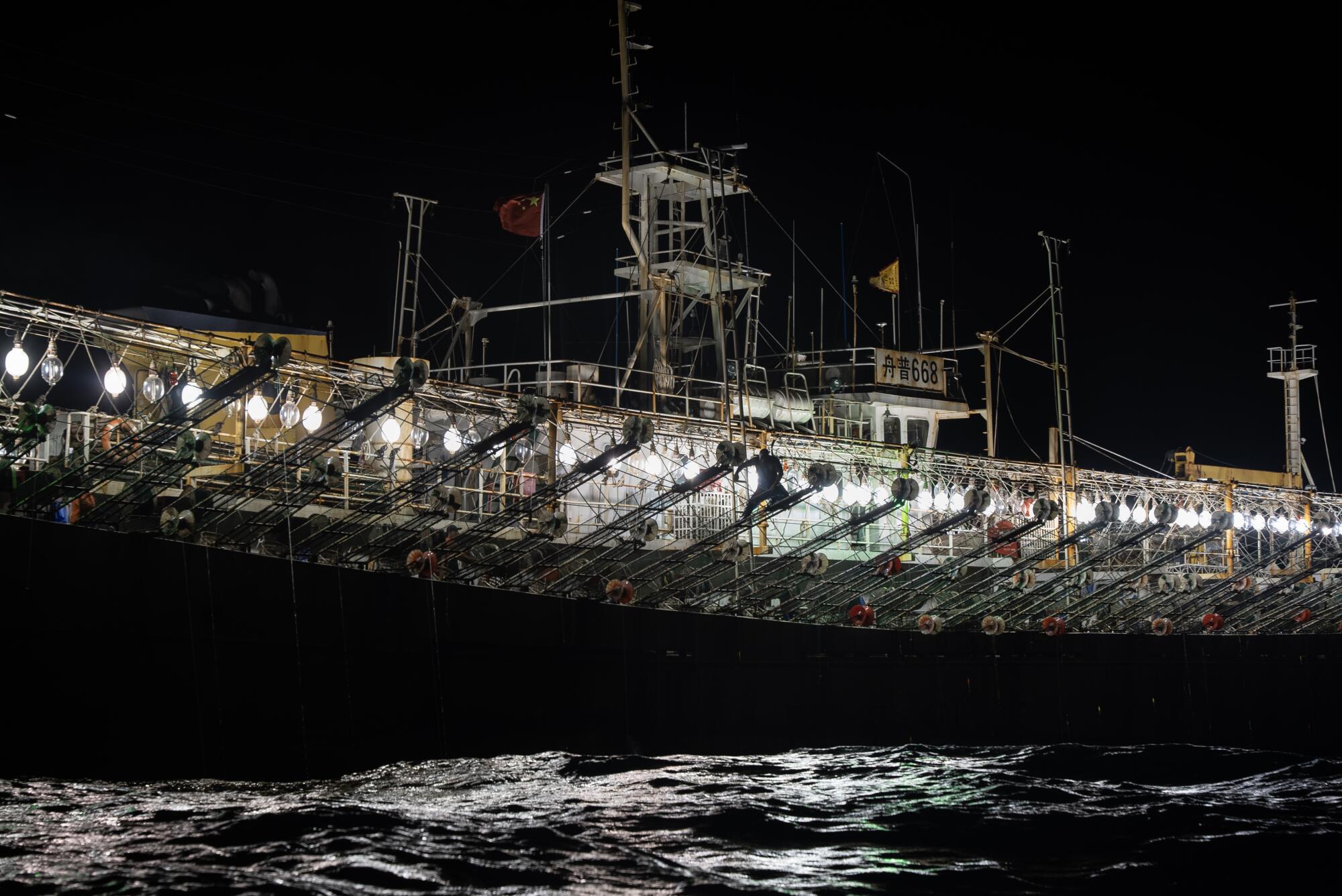 Hundreds of bright light bulbs adorn the side of a ship in darkness
