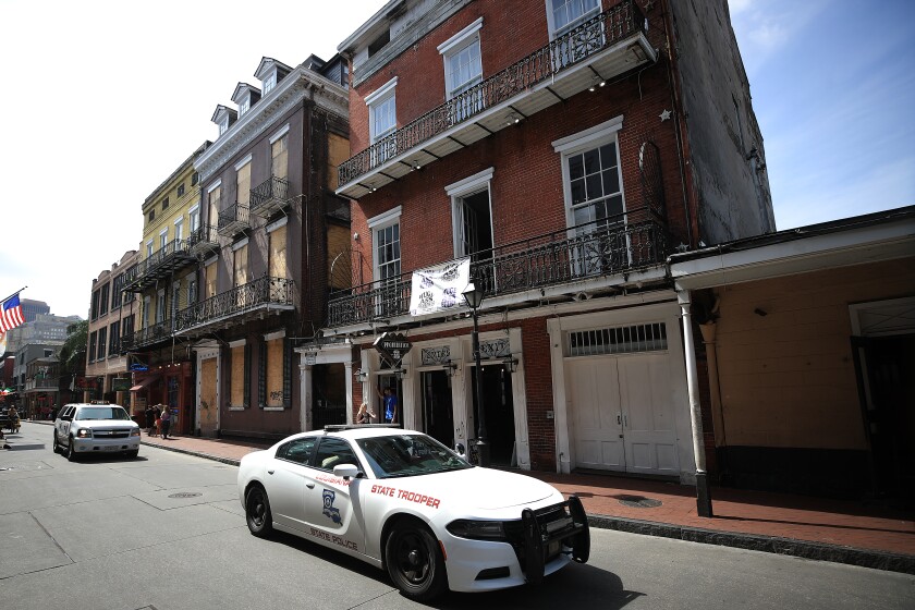 A state trooper car drives down a deserted Bourbon Street in New Orleans' French Quarter.