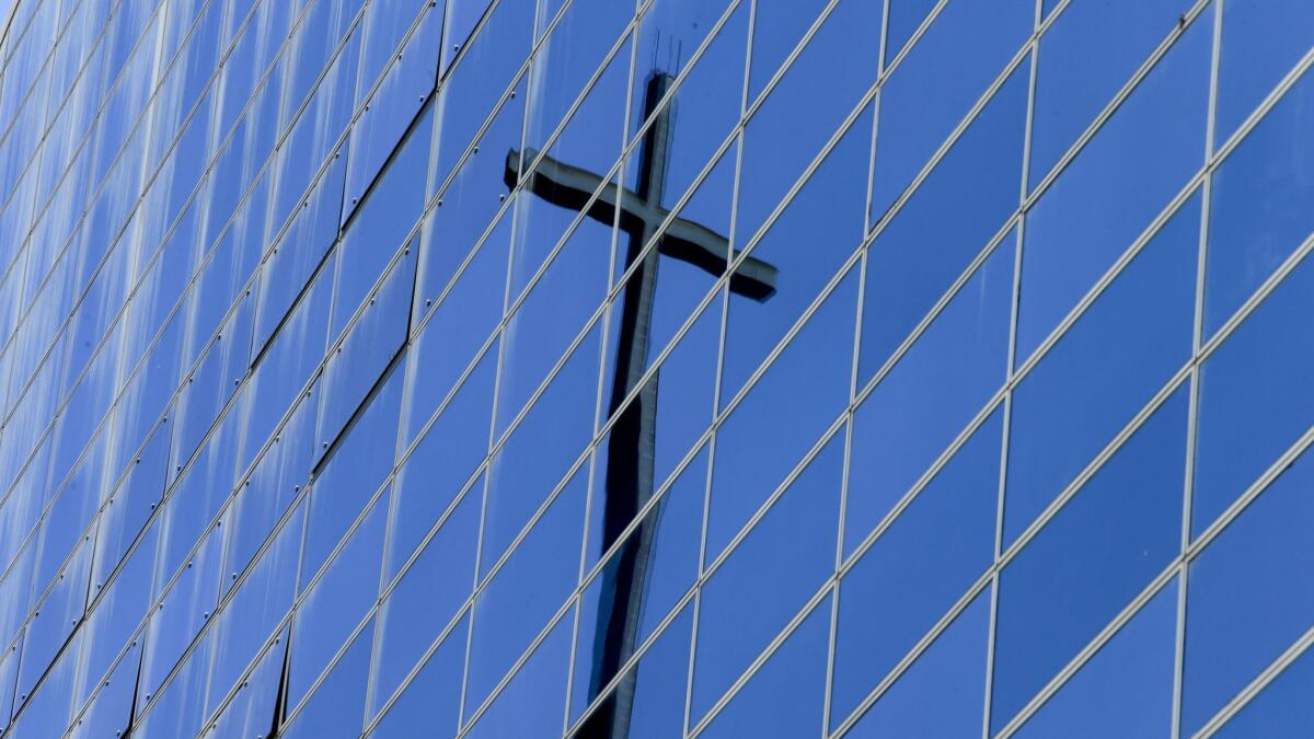 A cross atop the Roman Catholic Diocese of Orange is reflected in the former Crystal Cathedral in Garden Grove.