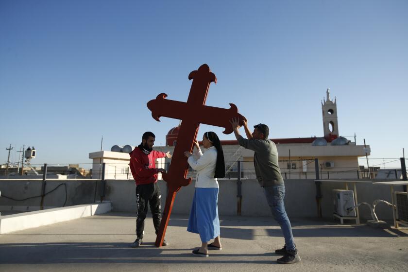 Iraqi Christians place a cross on a church in Qaraqosh, Iraq, Monday, Feb. 22, 2021. Iraq's Christians are hoping that a historic visit by Pope Francis in March will help boost their community's struggle to survive. The country's Christian population has been dwindling ever since the turmoil that followed the 2003 U.S.-led invasion. And it was dealt a near death blow in 2014, when Islamic State group militants overran northern Iraq, site of Iraq's historical Christian heartland. (AP/Photo/Hadi Mizban)