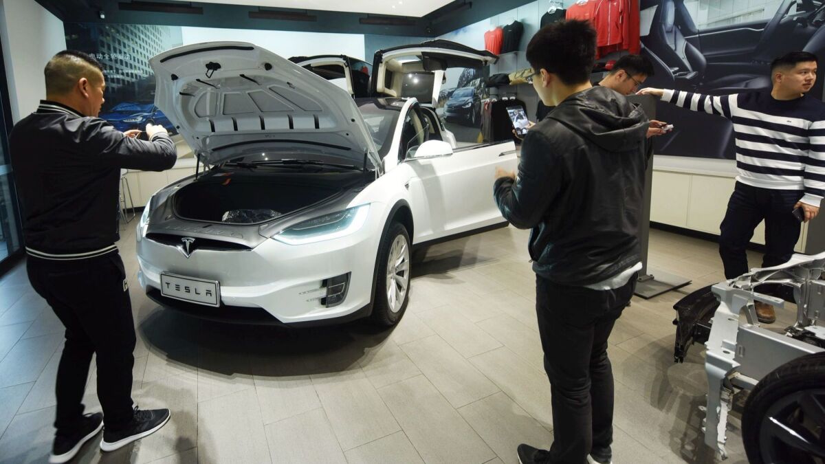 Customers look at Tesla cars at a showroom in Hangzhou in China's eastern Zhejiang province.