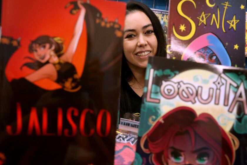 LOS ANGELES, CA - NOVEMBER 20, 2021 - Latina comic book creator Kayden Phoenix is framed by her graphic novels, "Jalisco," "Sonia," and "Loquita," at Comics Factory in Pasadena on November 20, 2021. Phoenix has made 5 comic books that concentrate on different aspects of societal injustice like, domestic violence, immigration and teen suicide, through Latina superheroes characters that she's created. Phoenix is also an award-winning director from the Boyle Heights. Her last film, "Penance," won honors at the L.A. Film Awards and Espantomania (Brazililian horror festival) and was shown at Cinequest and Outfest. Along with her film work, Kayden is the founder of non-profit Chicana Director's Initiative and recipient of Panavision's New Filmmaker's Program. (Genaro Molina / Los Angeles Times)