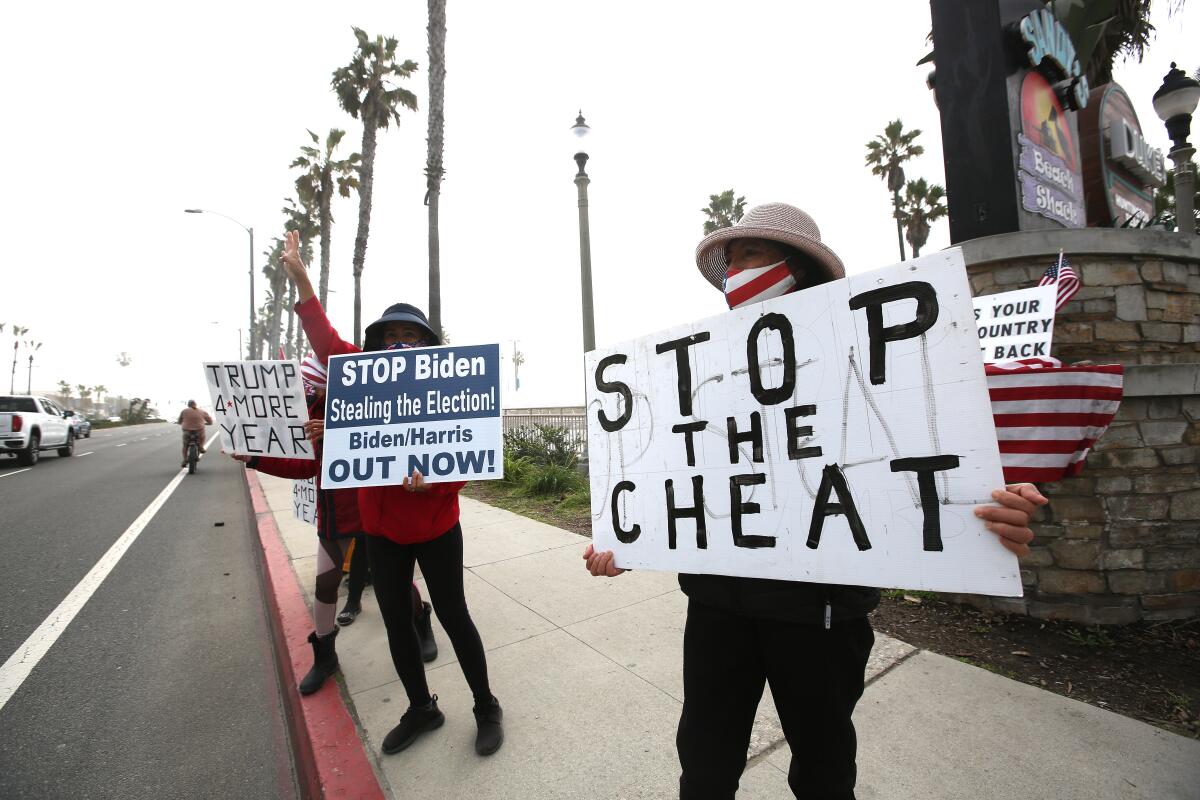 People hold a variety of signs during an election rally at the Huntington Beach Pier on Wednesday.