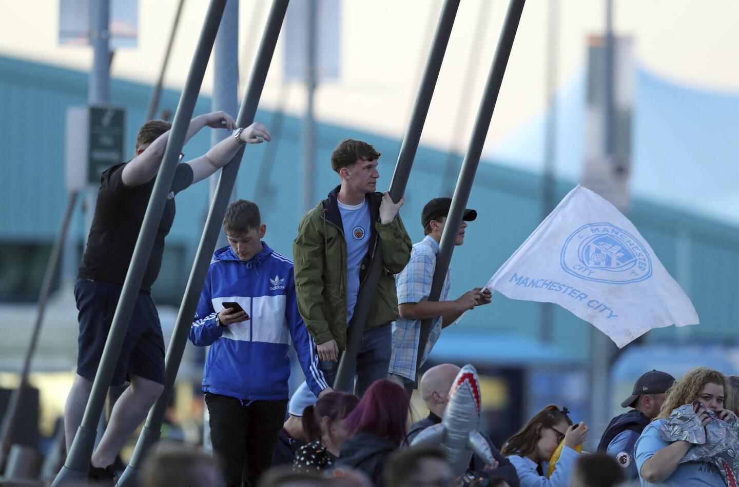 Manchester City supporters gather as they await the arrival of the team to celebrate at the team's Etihad Stadium the day they won the English Premier League title, in Manchester, England, Sunday May 12, 2019. Manchester City retained the Premier League trophy after coming from behind to beat Brighton 4-1 and see off Liverpool's relentless challenge on the final day of the season on Sunday. The quality and intensity of the title race was emphasized by City requiring a 14th successive league victory to finish a point above a Liverpool side chasing a first championship crown in 29 years as the top two finished with a record 195 points combined.(AP Photo/Jon Super)