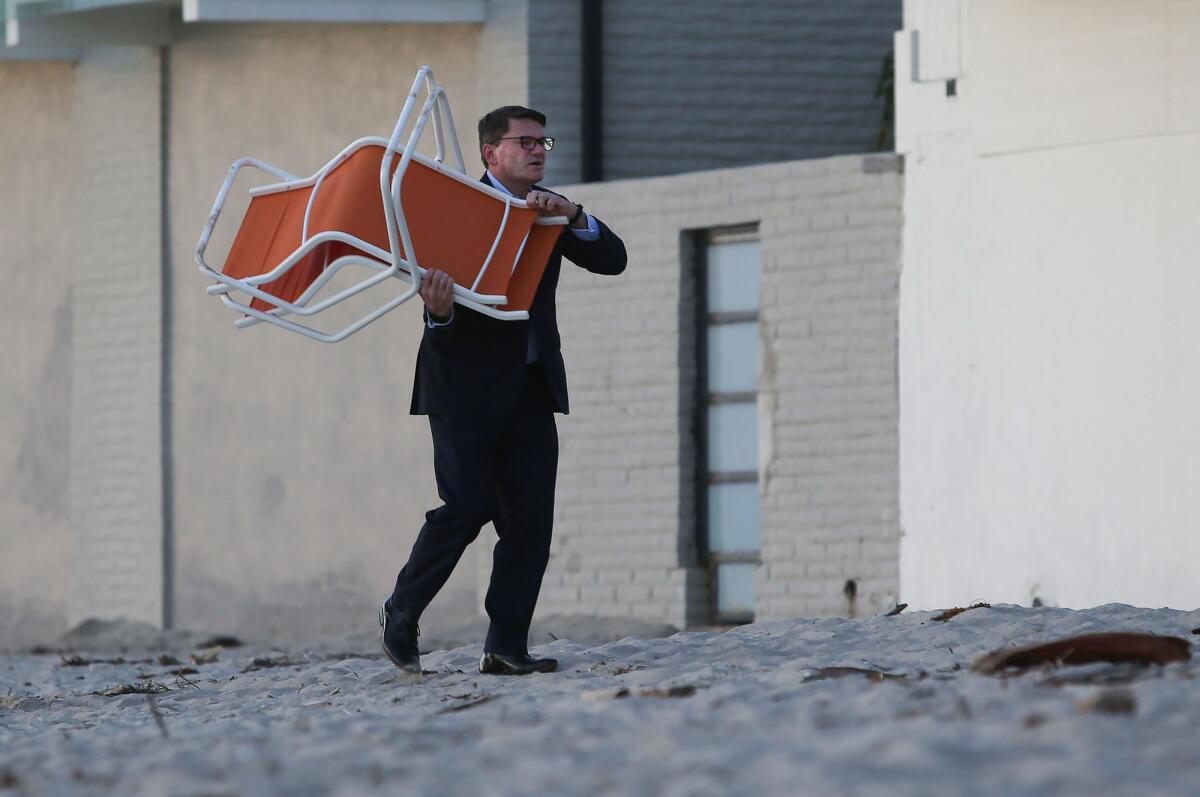 A manager at Pacific Edge hotel removes beach chairs Monday morning as Laguna Beach announced beach and park closures.