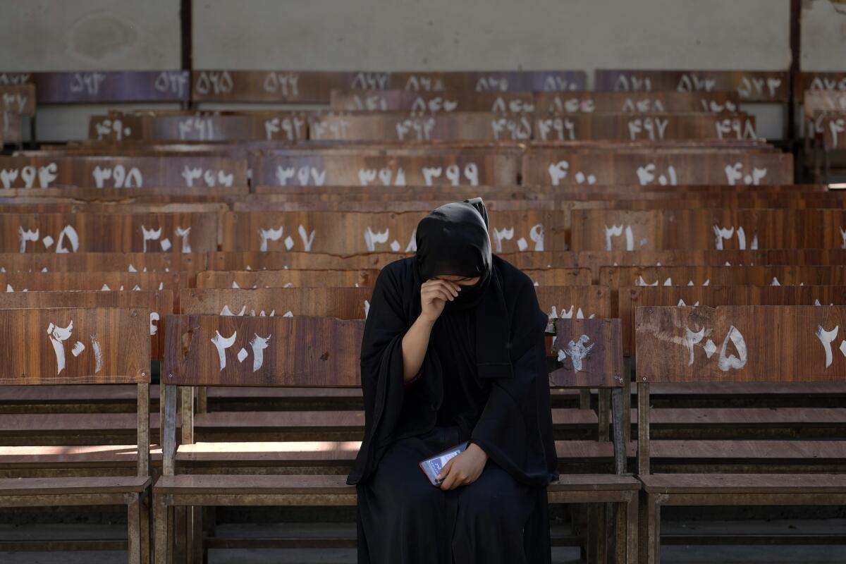 A Hazara Afghan girl sits and cries on the bench