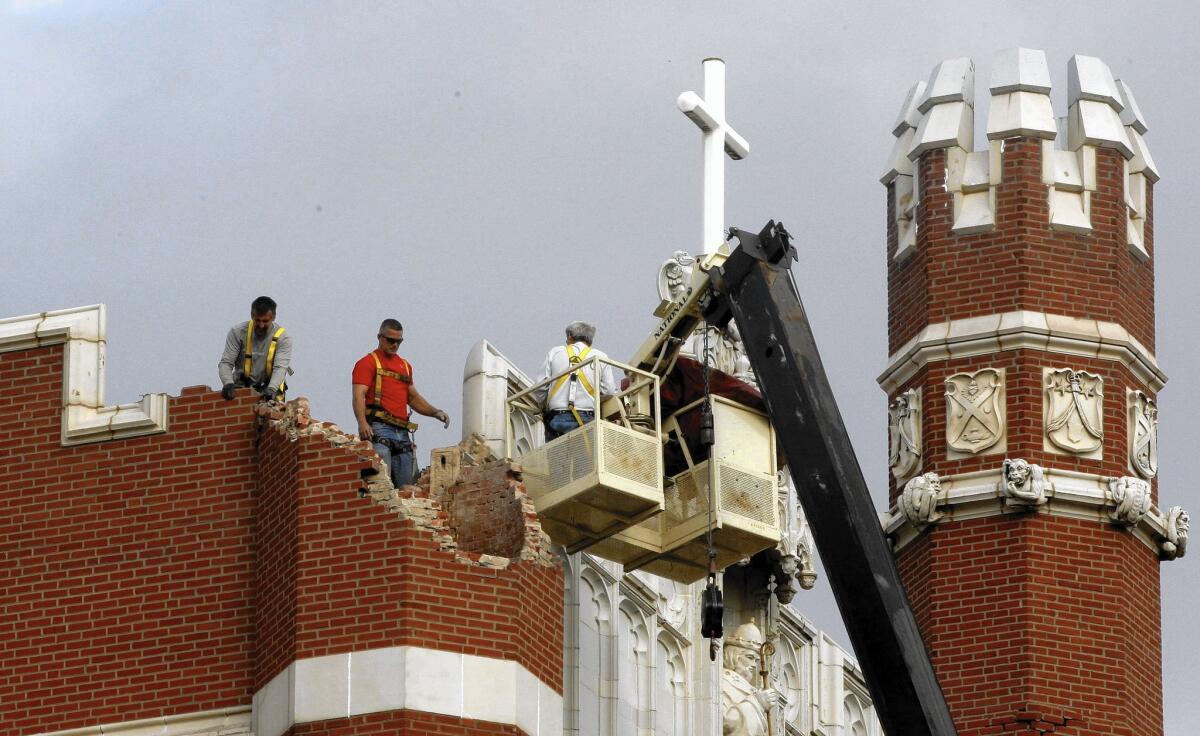 Maintenance workers inspect the damage to one of the spires on Benedictine Hall at St. Gregory's University after a magnitude-5 earthquake in Shawnee, Okla., in 2011.