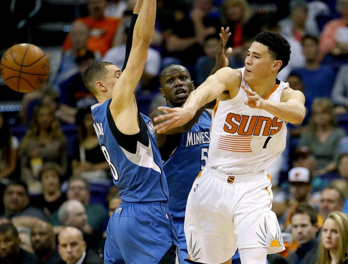 Suns rookie Devin Booker, right, passes around the Timberwolves' Zach LaVine during the first half of a game on March 14. (Matt York / Associated Press)