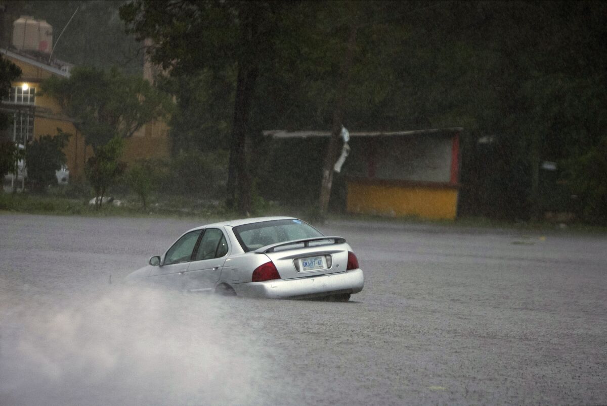 A car is stuck in a flooded street due to Hurricane Rick in Lazaro Cardenas, Mexico, Monday, Oct. 25, 2021. Hurricane Rick roared ashore along Mexico's southern Pacific coast early Monday with winds and heavy rain amid warnings of potential flash floods in the coastal mountains. (AP Photo/Armando Solis)