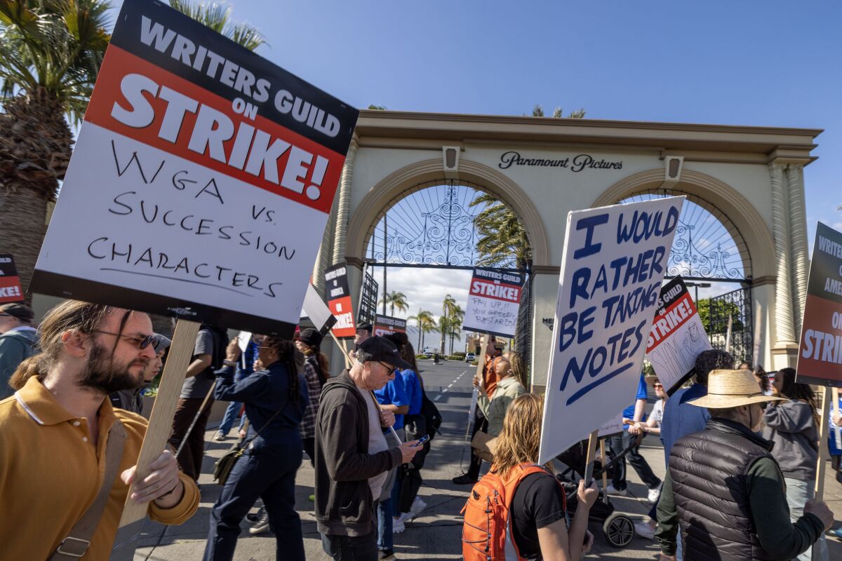 One picketer's sign reads, 'WGA vs. Succession characters' as writers strike outside Paramount.