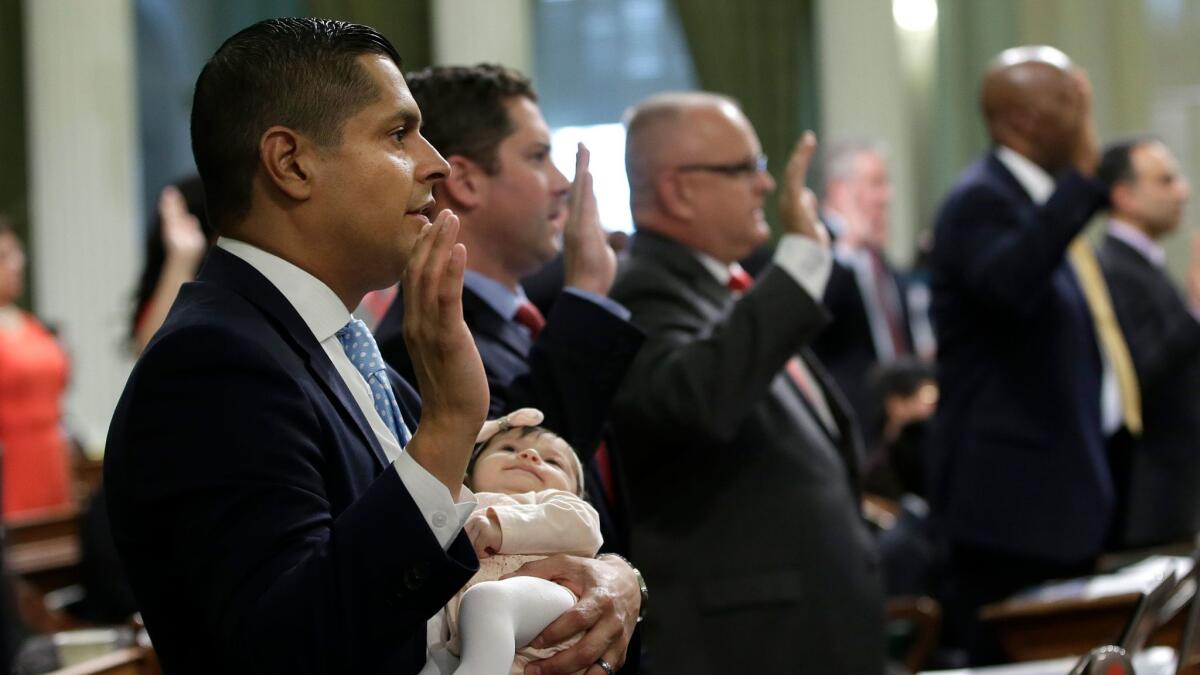 Assemblyman Miguel Santiago (D-Los Angeles), shown holding his daughter Brielle as he and the rest of the state Assembly are sworn into office in December, has introduced a bill targeting the passage of slow-growth ballot measures.