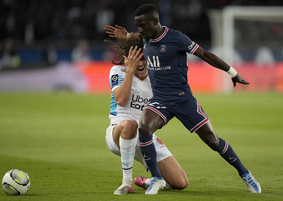 Marseille's Matteo Guendouzi, left, duels for the ball with PSG's Idrissa Gueye during the League One soccer match between Paris Saint Germain and Marseille, at the Parc des Princes stadium, in Paris, France, Sunday, April 17, 2022. (AP Photo/Francois Mori)